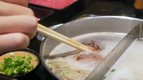 Chopstick with beef put into hot boiling water in hotpot soup.Shot in 4K. Delicious home cooking in