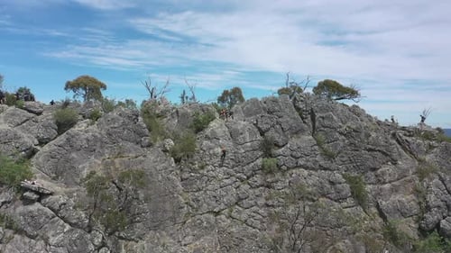 Student slowly rappels steep rugged rock of Sugarloaf mountain, VIC