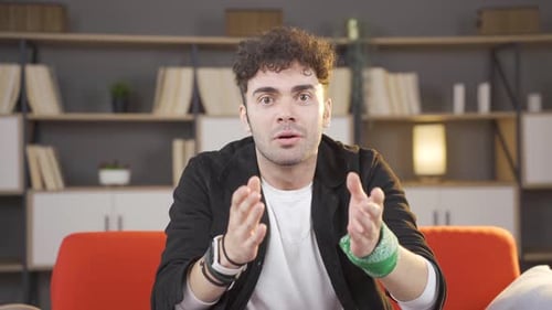 Man Reacts with Surprise While Sitting on Sofa