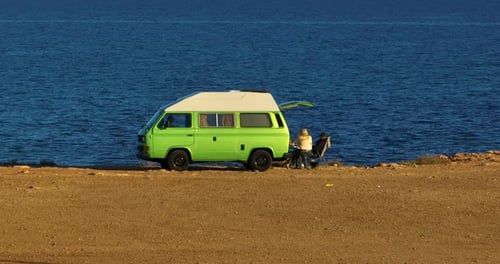 Group of People Relaxing in Nature with a Motorhome Standing on a Cliff Above the Sea Holiday in a