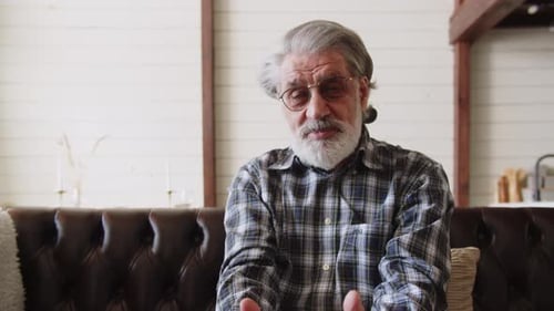 Senior Man Speaking on Couch Indoors