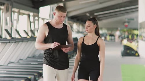 Gym Personal Trainer Coaching Young Woman on Workout