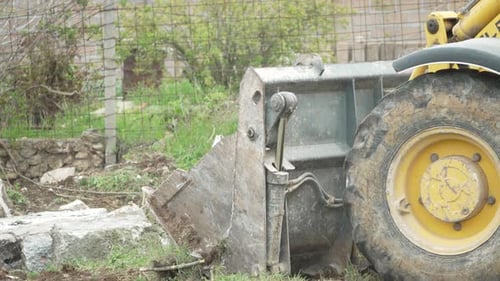 Excavator Heavy Equipment Rock Frontend Loader Bucket Picks Up Large Stone at Construction Site