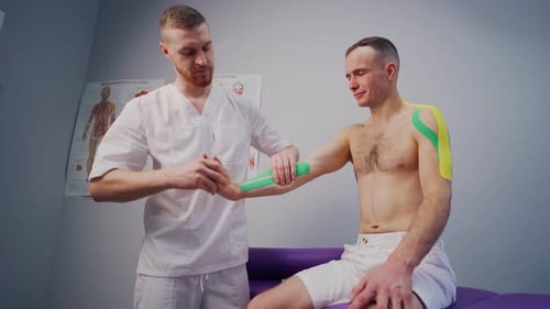 Doctor Applying Kinesiology Tape to a Man's Arm