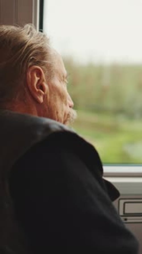 Senior Man Looks Out of Train Window