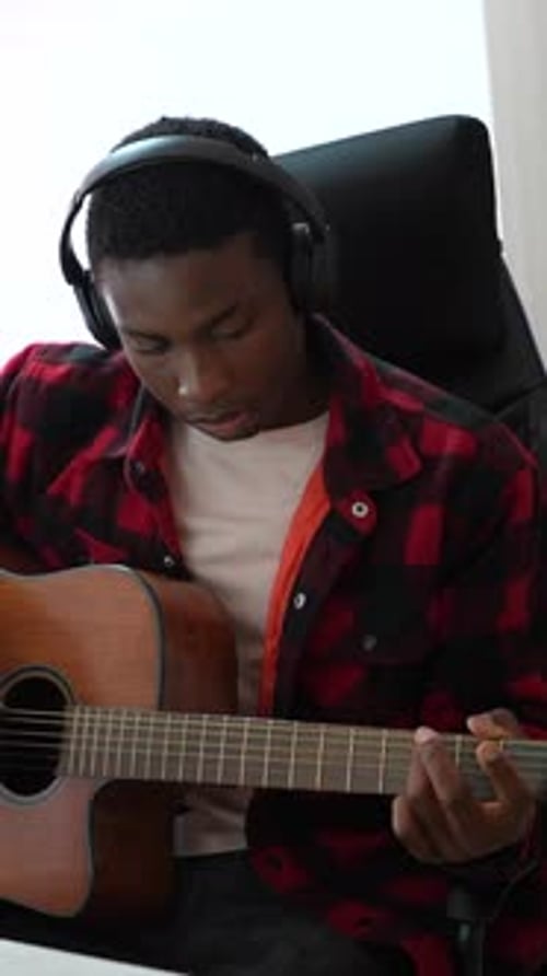 Young musician recording guitar track in home studio