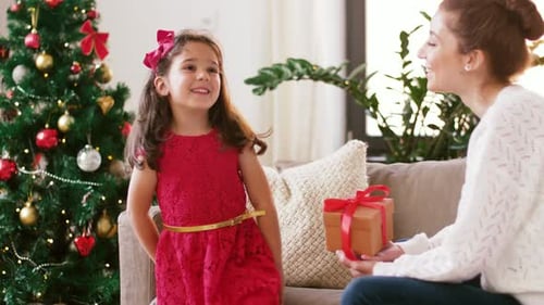 Little Girl Receiving a Christmas Gift From Mother