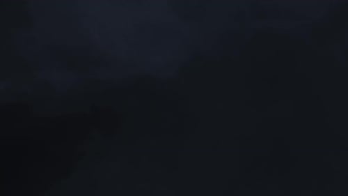 Lightning flashes through dark storm clouds