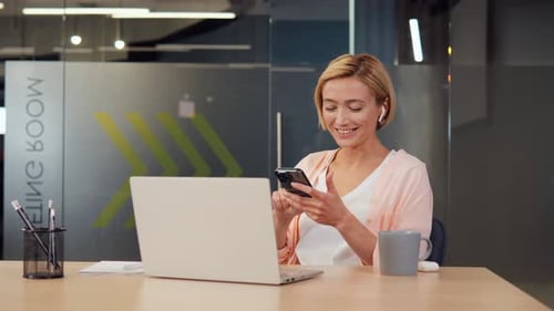 Woman Uses Mobile Phone at Desk in Office