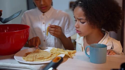 Children Enjoying Fresh Pancakes in Bright Kitchen