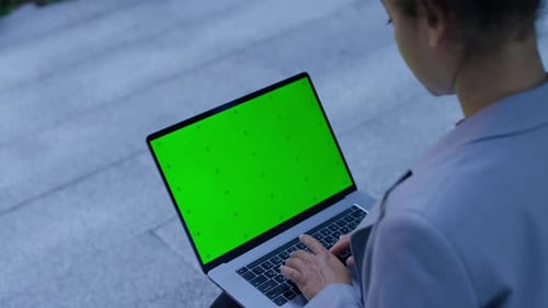 Woman Typing on Laptop with Green Screen Outdoors
