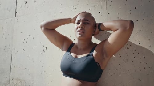 Athletic Woman Leaning Against a Concrete Wall