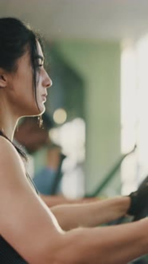 Beautiful Concentrated Athletic Women and Men Training on Treadmill Cross Trainer Together Working