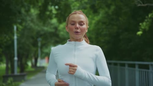 Woman Jogging on a Path in a Green Park