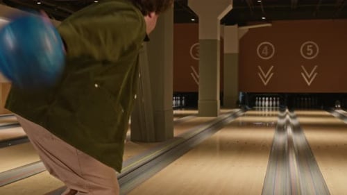 Mann wirft Bowlingkugel in der modernen Bowlingbahn die Gasse hinunter