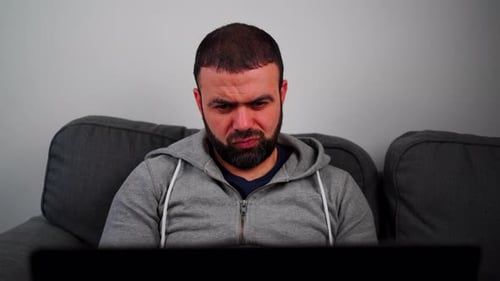 Middle Eastern Man With Beard Seriously Working On His Laptop At Home. Close-up Shot