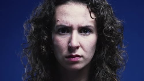 Woman frowning head and looking directly at camera with angry expression, person shakes