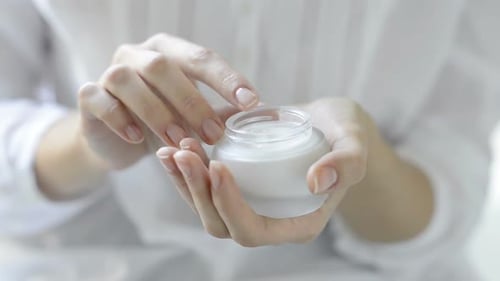 Closeup of Hands Applying Moisturizer. Beauty Woman Holding a Glass Jar