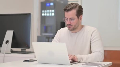 Young Man Working on Laptop in Office