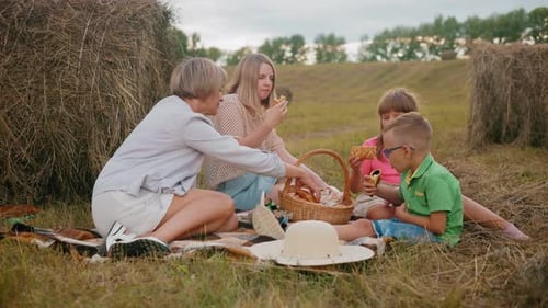 Family Picnic on Grassy Field with Hay Bales