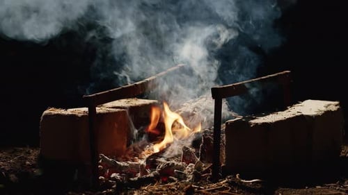 Burning Firewood with Rising Smoke and Embers in Outdoor Barbecue Grill Closeup of Campfire with