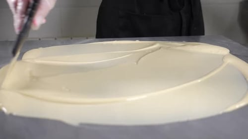 Tempering Chocolate Chef Mixes Melted Chocolate with Metal Spatula on Stone Table in Pastry Shop