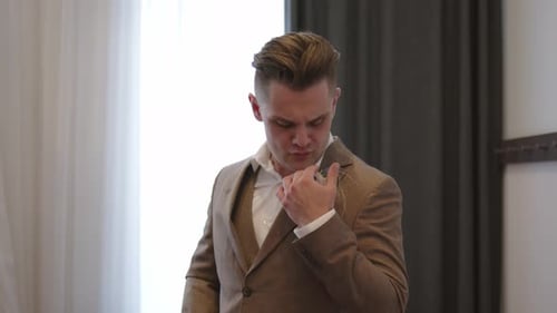 Handsome Groom Adjusting His Boutonniere Indoors