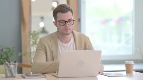Man Working on Laptop at Desk in Office