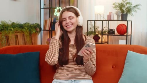 Young Woman Enjoys Music on Phone at Home