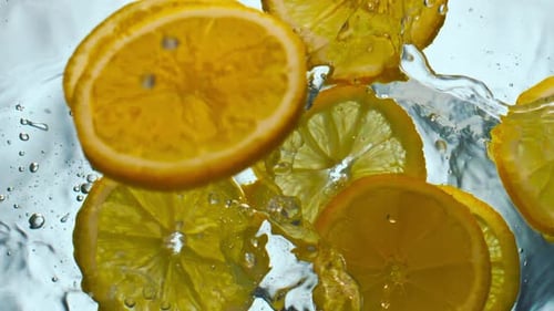 Slices of citrus fruit falling into water