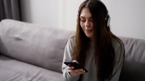 Woman Listening to Music on Smartphone on Couch