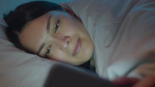 Woman Using Smartphone in Bed at Night