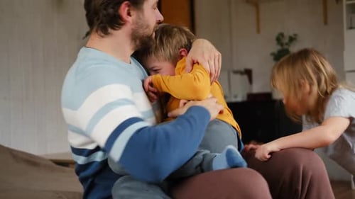 Father Playing With Children on Bed in Home
