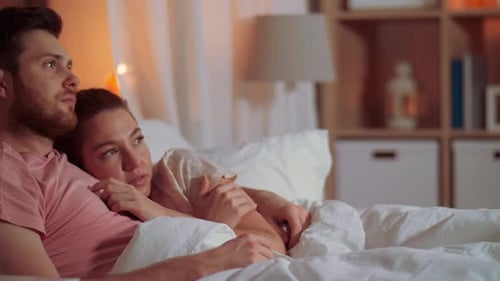Loving Couple Watching Movie in Bed at Night