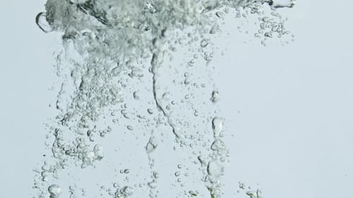 Limes dropping into water with many bubbles