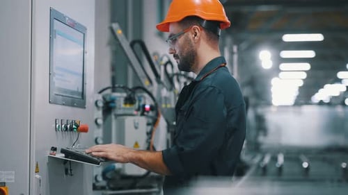 Einstellungen der Maschine anpassen, bedienen. Der Fabrikarbeiter ist mit Schutzhelm drinnen.