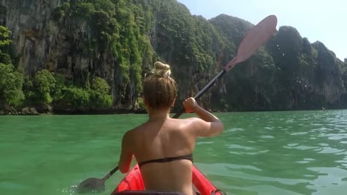 Close Up of the Back of a Girl Kayaking on the Sea Close to Beautiful Mountains.