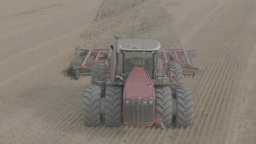 Descartando o trator de campo cultivando a terra de Disc Harrow Vista frontal do trator vermelho em funcionamento