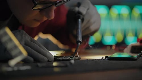 Technician Repairing Cellphone with Soldering Iron Close-Up