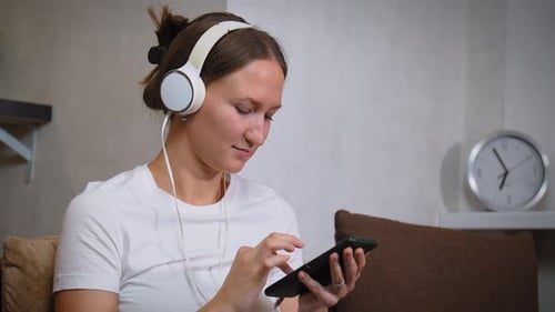 Woman Listening with Headphones Using Smartphone Indoors
