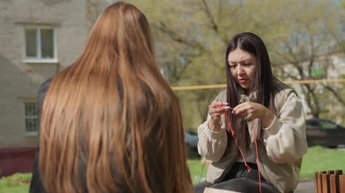 Friends Collaborate on Knitting Project in Urban Park Setting Women Exchanging Knitting Advice While