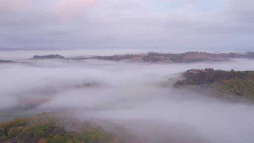 Mist covering rural forests of Tuscany in Italy, aerial