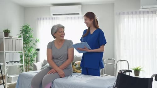 Asian caregiver explain diagnosis to senior woman at nursing home care.