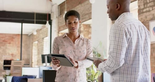 Young African American businesswoman and businessman discuss work in an office
