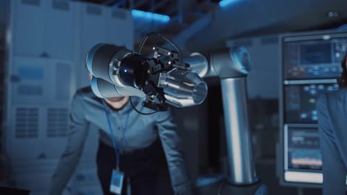 Futuristic Metal Robotic Arm Moving a Small Object and Placing It. Team of Engineers Observe This A