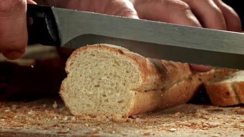 Der Koch schneidet frisches Brot, gefilmt mit einer Hochgeschwindigkeitskamera mit 1000 Bildern pro Sekunde