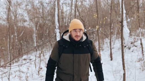Man Hiking Through Snow in a Winter Forest