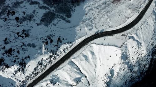 Kurvenreiche Straße durch eine verschneite Berglandschaft, Luftaufnahme