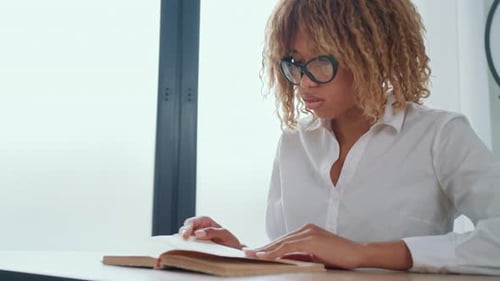 Woman Reading Book at Desk Indoors