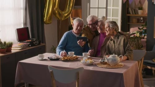 Seniors Gather for Birthday, Laughing at Phone
